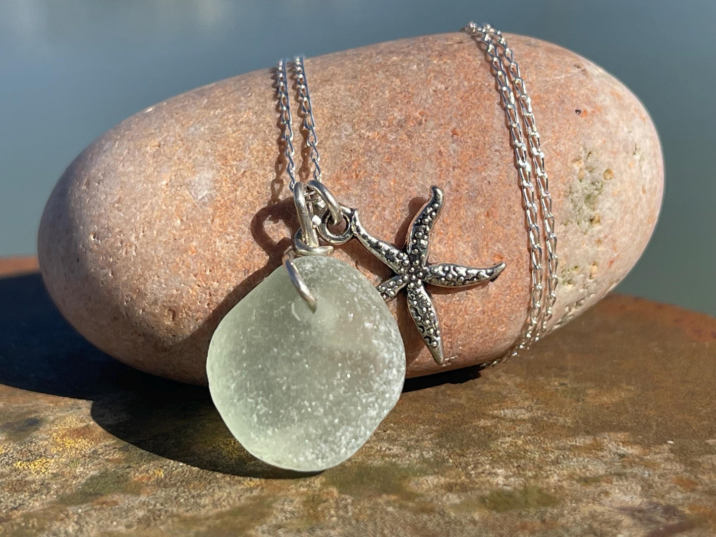 Eco friendly white sea glass necklace on a sterling silver chain showcasing a little starfish. Starfish pendant, eco friendly jewellery.
